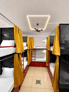 a room with three bunk beds with yellow curtains at Inka Kashi Hostel Varanasi in Varanasi