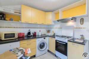 a kitchen with yellow cabinets and a washing machine at Maison venitia t1 in Aussonne +19 photos