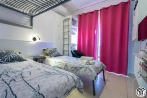 two beds in a room with red curtains at Maison venitia t1 in Aussonne
