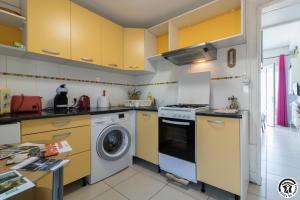 a kitchen with yellow cabinets and a washing machine at Maison venitia t1 in Aussonne
