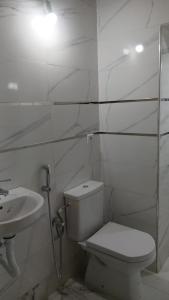a white bathroom with a toilet and a sink at Only in M'diq