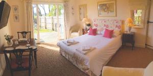 a bedroom with a large white bed with pink pillows at Fox Inn in Darsham