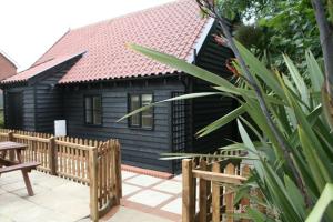 a black house with a wooden fence in front of it at Fox Inn in Darsham