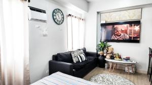 a living room with a black couch and a tv at The Nook at Park in Ibaba