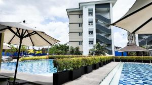 a hotel swimming pool with an umbrella and a building at The Nook at Park in Ibaba