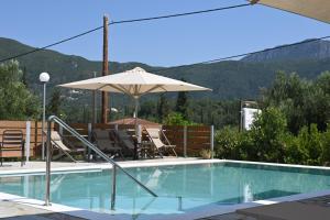 a swimming pool with an umbrella and chairs at Villa Avra in Dassia
