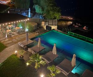a swimming pool with chairs and umbrellas at night at Donau Resort in Eşelniţa