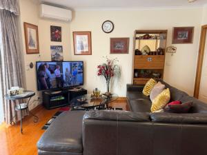 a living room with a couch and a tv at Bethel Homestay in Watsonia North