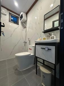 a bathroom with a toilet and a sink and a mirror at ILLUMI Homestay in Dong Hoi
