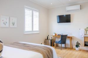 a bedroom with a bed and a desk and a tv at Whispering Oaks Guest House in George