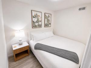 a white bedroom with a bed and a night stand with a lamp at The Oak & Aura Retreat in St. Charles