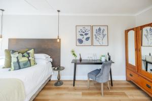 a bedroom with a bed and a desk with a chair at Whispering Oaks Guest House in George +61 photos