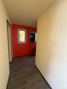 an empty room with red walls and wooden floors at Alvin Relax in El Cajon