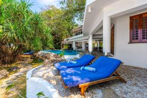 a patio with blue lounge chairs and a pool at Tequila Sunrise Beach Villa-Diani Beach in Diani Beach