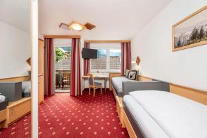 a hotel room with two beds and a desk at Pension Posauner in Dorfgastein