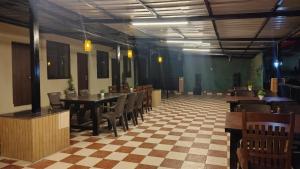 a dining room with a checkered floor and tables and chairs at Hotel Skyline in Kanatal