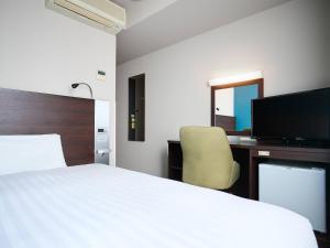a bedroom with a bed and a desk and a television at Comfort Hotel Sendai West in Sendai