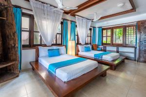 two beds in a room with blue curtains and windows at Tequila Sunrise Pool Cabana-Diani Beach in Diani Beach +71 photos