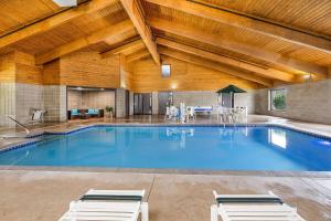 a large swimming pool with two lounge chairs in a building at AmericInn by Wyndham Albert Lea in Albert Lea