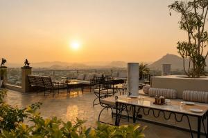 a rooftop patio with tables and chairs and the sunset at Raj Kuber - A Boutique Lake View Hotel in Udaipur +65 photos
