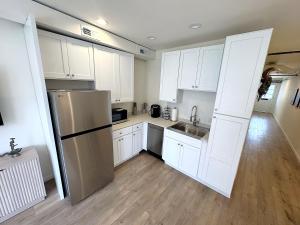 a kitchen with white cabinets and a stainless steel refrigerator at The Rustic Revival - Charming 2BR Retreat in St. Charles