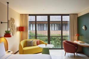 a hotel room with a bed and a chair and a table at Kleo Seminyak, part of JdV by Hyatt in Seminyak