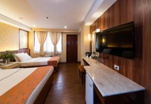 a hotel room with two beds and a flat screen tv at Hotel Veniz in Baguio