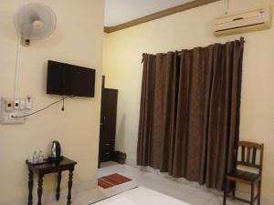 a room with a curtain and a television and a chair at Camellia Vang Vieng in Vang Vieng