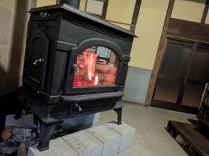 a stove with a fire in a room at ちょっとそこまで in Bessako