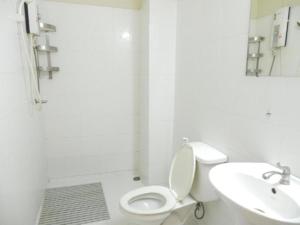 a white bathroom with a toilet and a sink at Camellia Vang Vieng in Vang Vieng