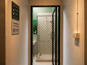 a door to a bathroom with a shower and a mirror at Smith & Appy Backpackers Hostel in Nathon Bay