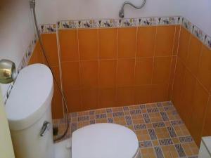 a bathroom with a toilet with an orange wall at Baan Gon Chompu in Suan Phung +66 photos