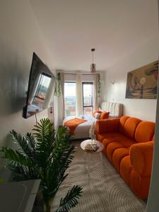 a living room with an orange couch and a bed at Suite Life in Kiambu