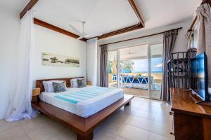 a bedroom with a bed and a television and a balcony at Tequila Sunrise Sky Cabana-Diani Beach in Diani Beach