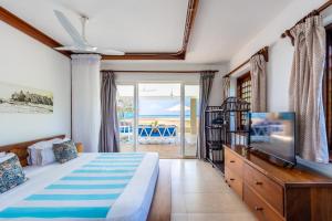 a bedroom with a bed and a tv and a balcony at Tequila Sunrise Sky Cabana-Diani Beach in Diani Beach +36 photos