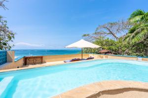 a swimming pool with an umbrella and the beach at Tequila Sunrise Sky Cabana-Diani Beach in Diani Beach