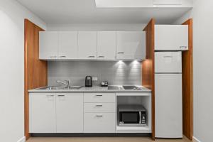 a kitchen with white cabinets and a microwave at Comfort Inn Geelong in Geelong