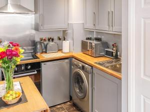 a kitchen with a washing machine and a vase of fruit at The Old Post Office in Kingskettle