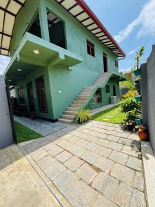 a green house with stairs in front of it at Sun land Villa in Hikkaduwa