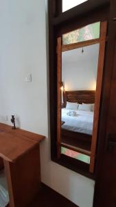 a mirror in a room with a bed and a desk at Kadura Resort in Ella