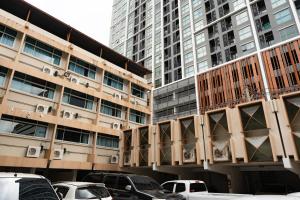 a parking lot with cars parked in front of tall buildings at Krungthai Hotel at Rangnam in Sathani Sam Sen
