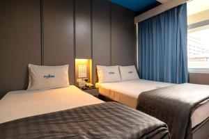 a hotel room with two beds and a window at Krungthai Hotel at Rangnam in Sathani Sam Sen
