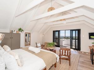 a bedroom with a large bed in a room with windows at L'abri in Langebaan