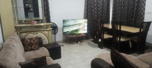 a living room with a tv and a couch and a piano at Axiom Services in Katamanso