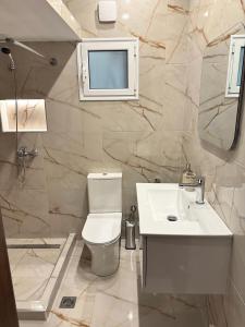 a bathroom with a toilet and a sink and a tv at Nikoletta in Katerini +16 photos