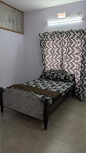 a bed sitting in a room with a wall at Janani service apartment in Kushālnagar
