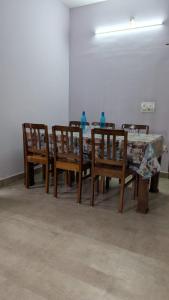 a dining room with a table and wooden chairs at Janani service apartment in Kushālnagar