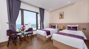 a hotel room with two beds and a table with chairs at Maison Hotel Phu Quoc in Phú Quốc +208 photos