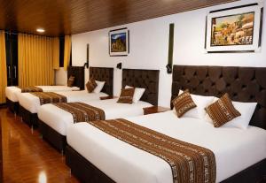 a row of four beds in a hotel room at Amakonkay Machupicchu in Machu Picchu
