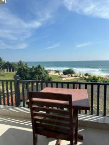 a wooden bench sitting on a balcony overlooking the beach at Sri Residence in Kamburugamuwa